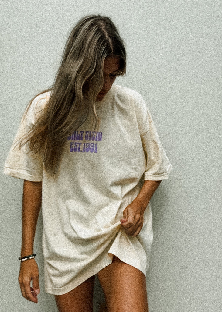 Woman wearing a white oversized t-shirt with text against a plain background