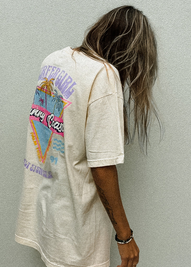 Person wearing a light-colored t-shirt with a colorful graphic design on the back, standing against a plain background.
