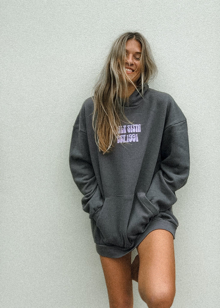 Person wearing a gray hoodie with text on it against a light gray background