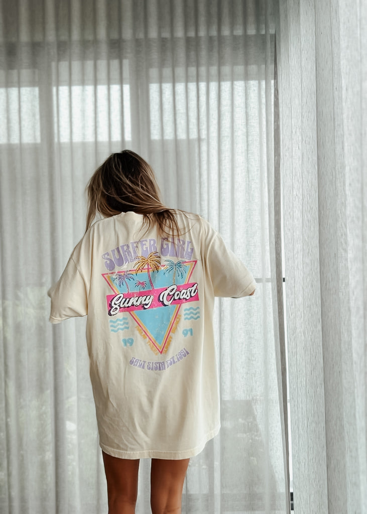Person wearing a t-shirt with a graphic design in front of sheer curtains