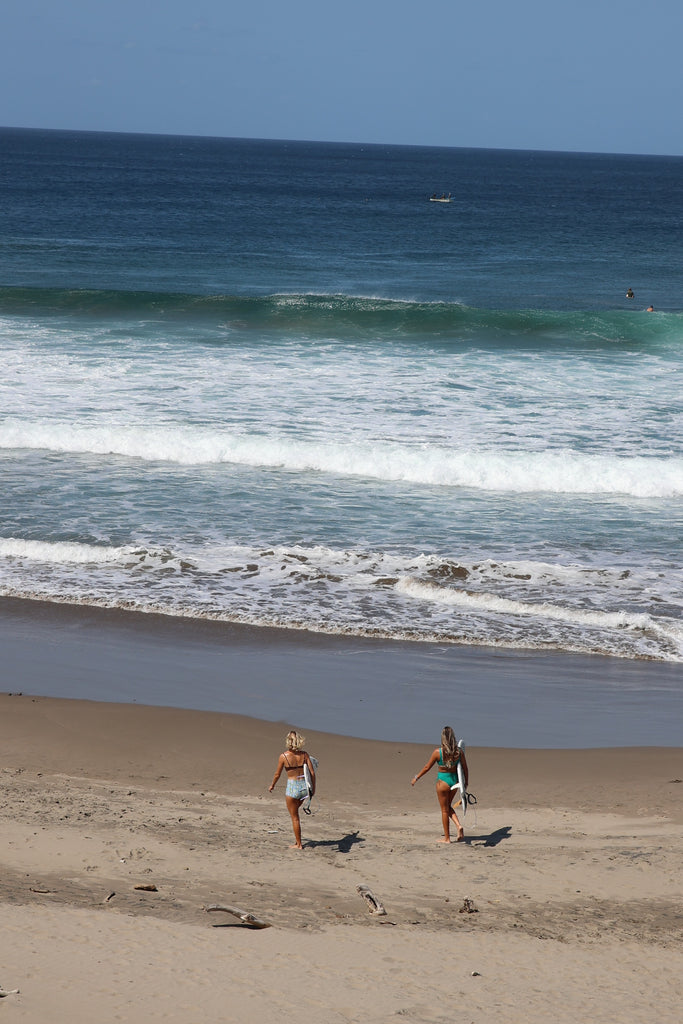 Two people walking on a sandy beach with ocean waves in the background